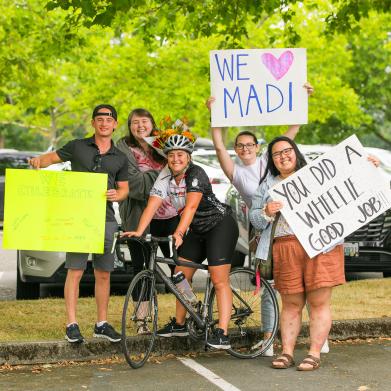 Smiling group holding signs of support for tour de cure bike rider