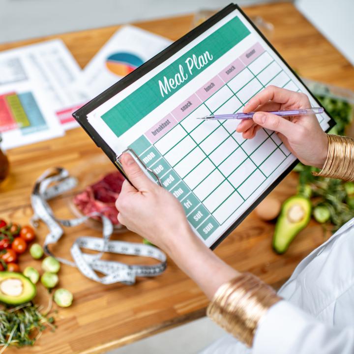 Person holding meal planning chart in front of veggies