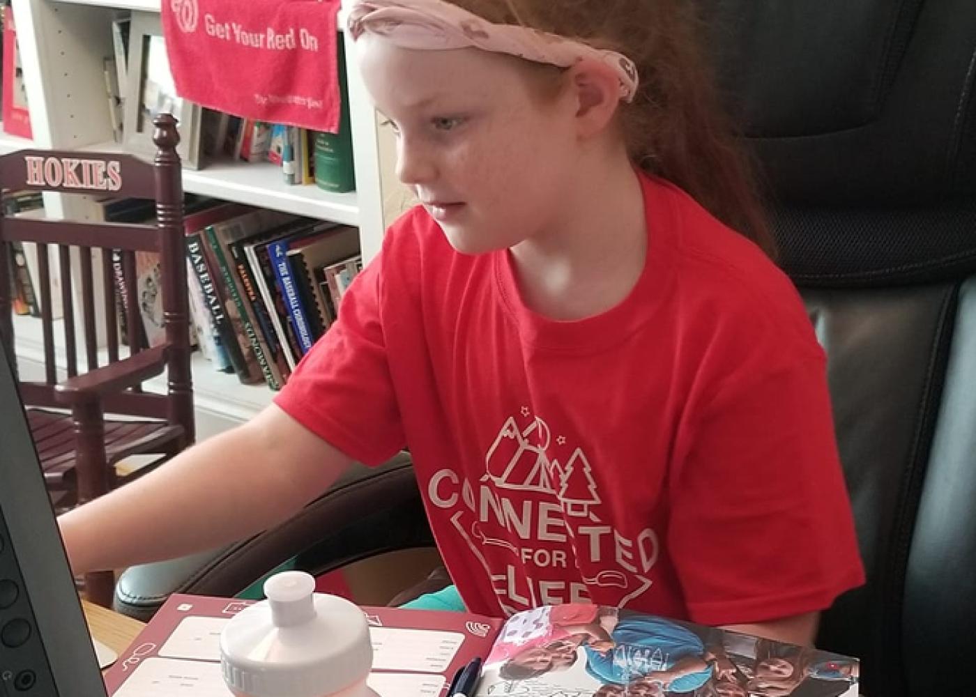 Girl in red shirt and pink bandanna at computer 