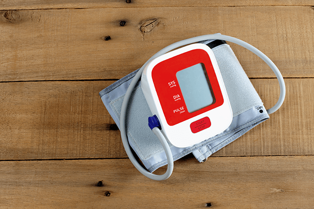 Red blood pressure cuff sitting on wood table surface